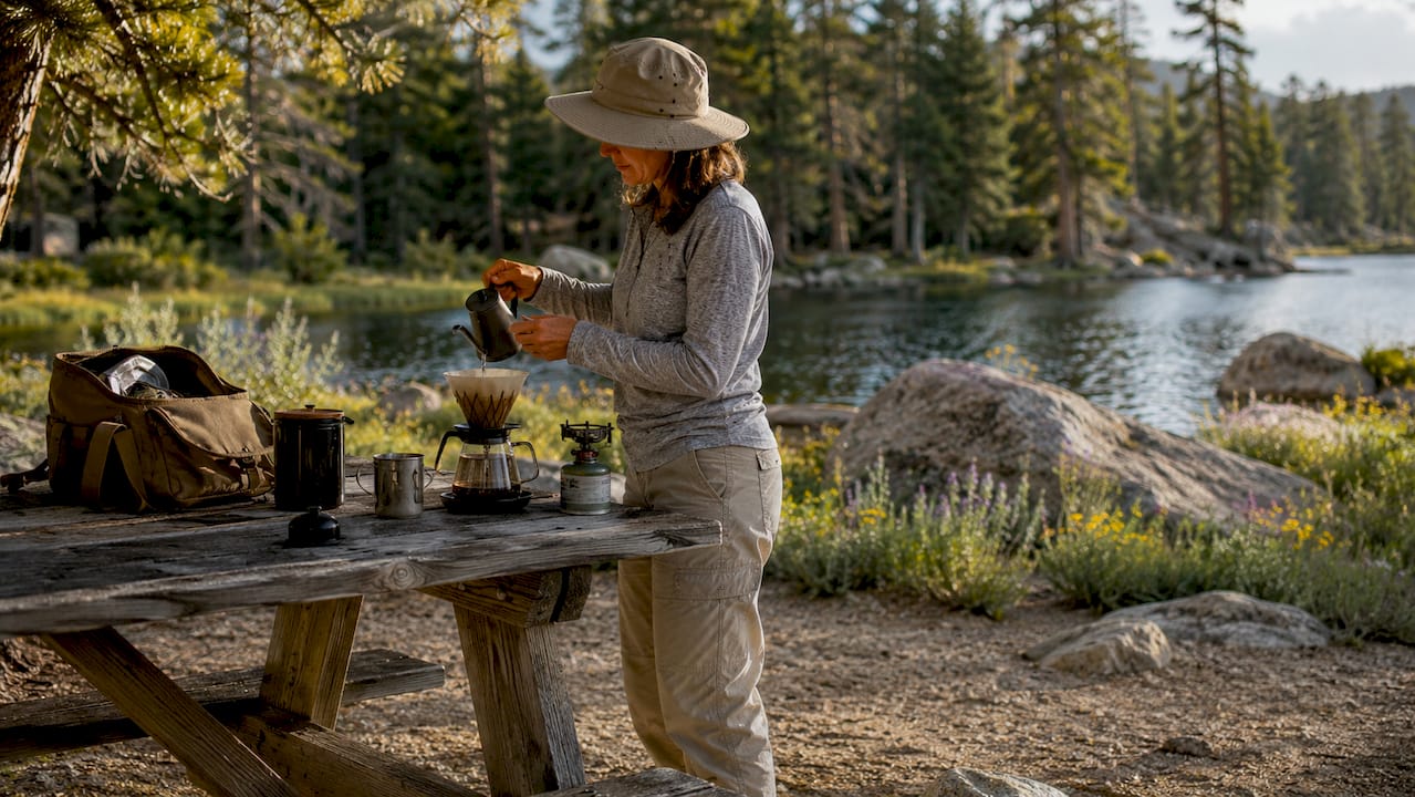 Woman brewing coffee outdoors at campsite