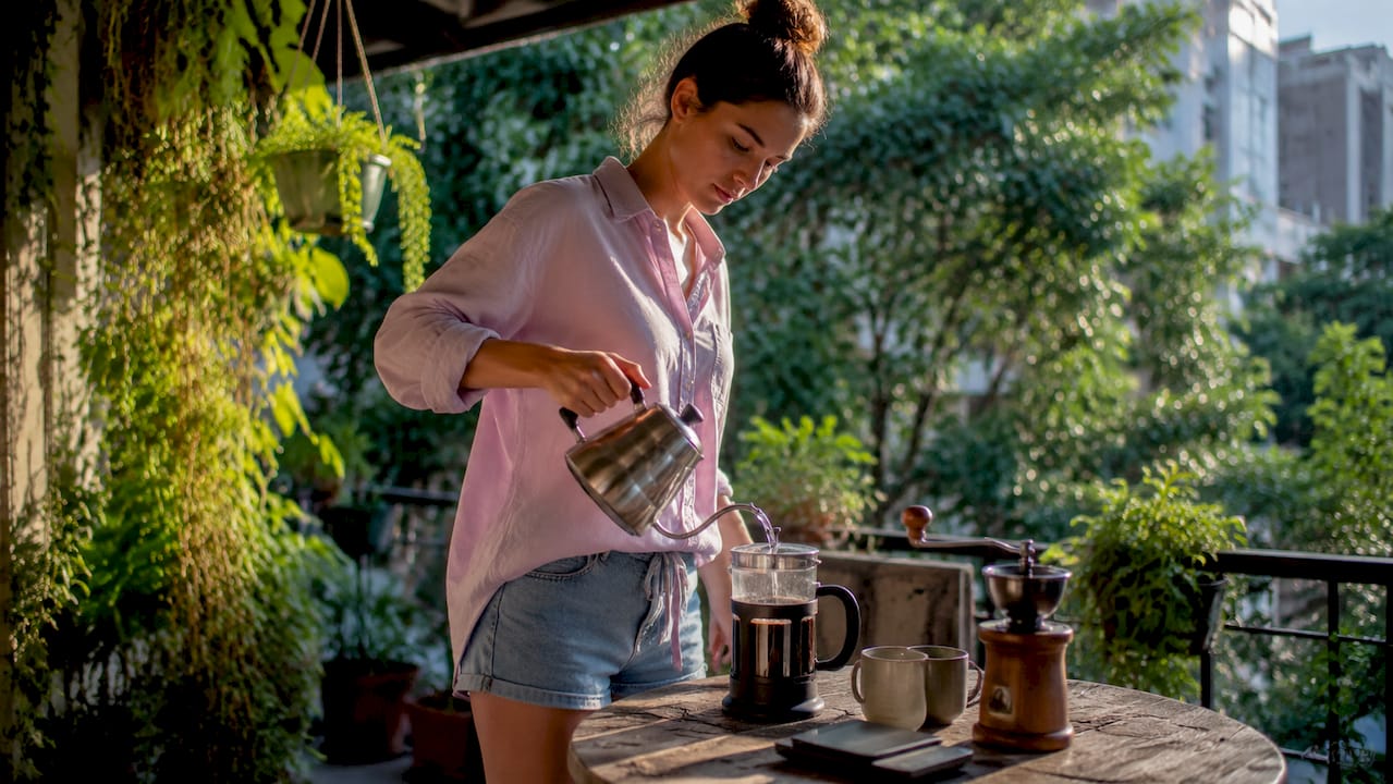 Woman brewing coffee with French press in kitchen