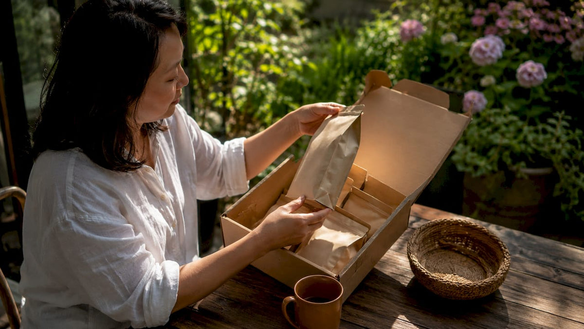 Woman unpacking curated coffee box at kitchen table